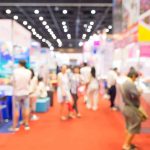 Trade show booth with custom printed balloons from CSA Balloons and branded décor attracting attendees in a busy exhibition hall.
