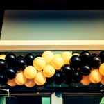Custom printed latex and mylar balloons from CSA Balloons displayed above grocery store promotional aisles